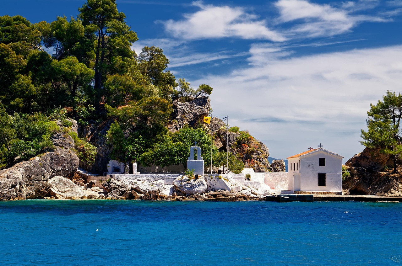 Tradiční řecká vesnice u Jónského moře, bílé domky s modrými dveřmi, olivovníky, pohled na moře