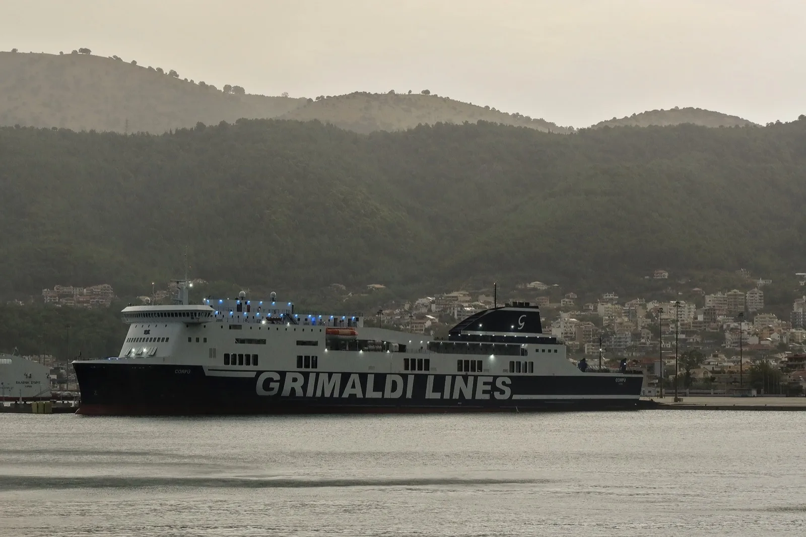 Trajekt Grimaldi Lines v přístavu Igoumenitsa, za ním město a zelené kopce