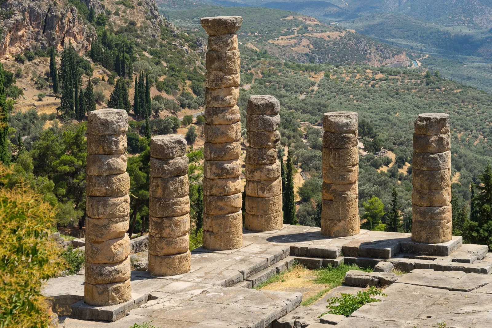 Šest dochovaných sloupů Apollónova chrámu v Delfách a údolí s olivami